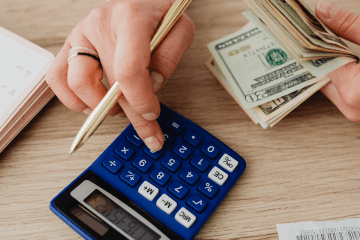 Image of a woman using a calculator at a desk for a post answering the question "how much do secret shoppers make?"