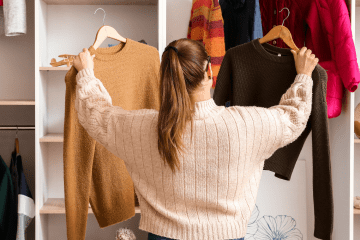 Image of a woman in a store comparing two sweaters for a post on how mystery shopping companies work.