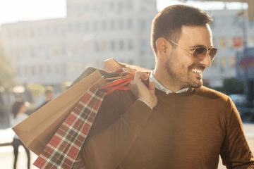 Image of a man outside of a shop with multiple bags for a post covering video mystery shopping.