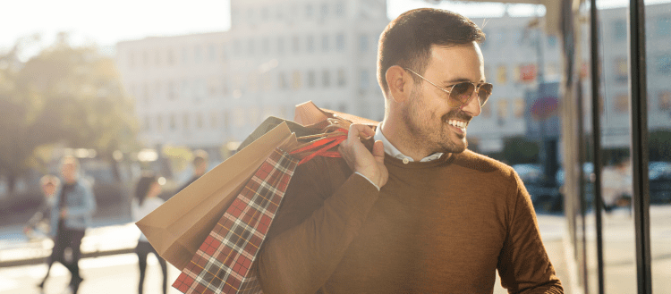 Image of a man outside of a shop with multiple bags for a post covering video mystery shopping.