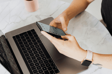 Image of a woman working on her laptop and phone for an article about working with mystery shopping schedulers.