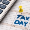 Image of a calculator and a calender marked "tax day" for a blog post covering the best tax software for mystery shoppers.