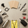 Image of a mystery shopper carry kit laid out in a flat-lay arrangement, including a portable charger, car phone mount, notebooks, pens, two Casio watches, a file folder, EDC pouch, insulated lunch bag, water bottle, safety vest, infrared thermometer, reading glasses, keychain tape measure, and ID badge holder on a neutral beige surface.