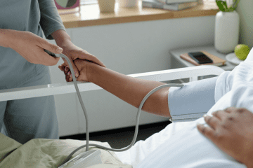 Image of a person in a hospital bed getting their blood pressure check for a post covering mystery shopping health insurance deductions.