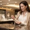 Image of a well-dressed woman examining fine jewelry at an upscale boutique counter during a luxury buyer pre-qualification mystery shop.